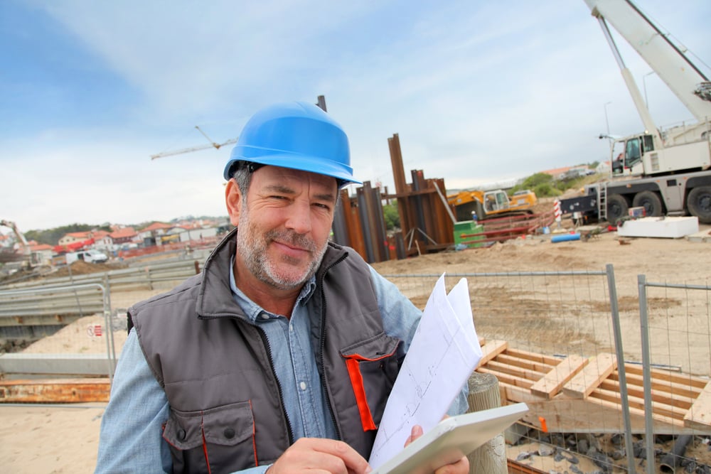 Construction manager controlling building site with plan